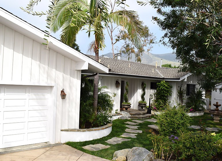 Exterior view of Cliffside Malibu, a residential treatment center in Malibu, California. View of the house and front yard with grass and stones.