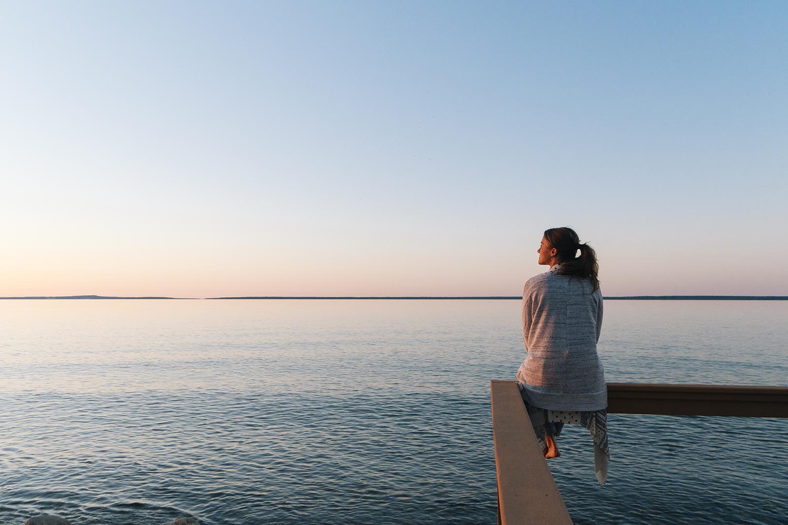 Young woman sitting on edge looks out at view in Malibu, California.