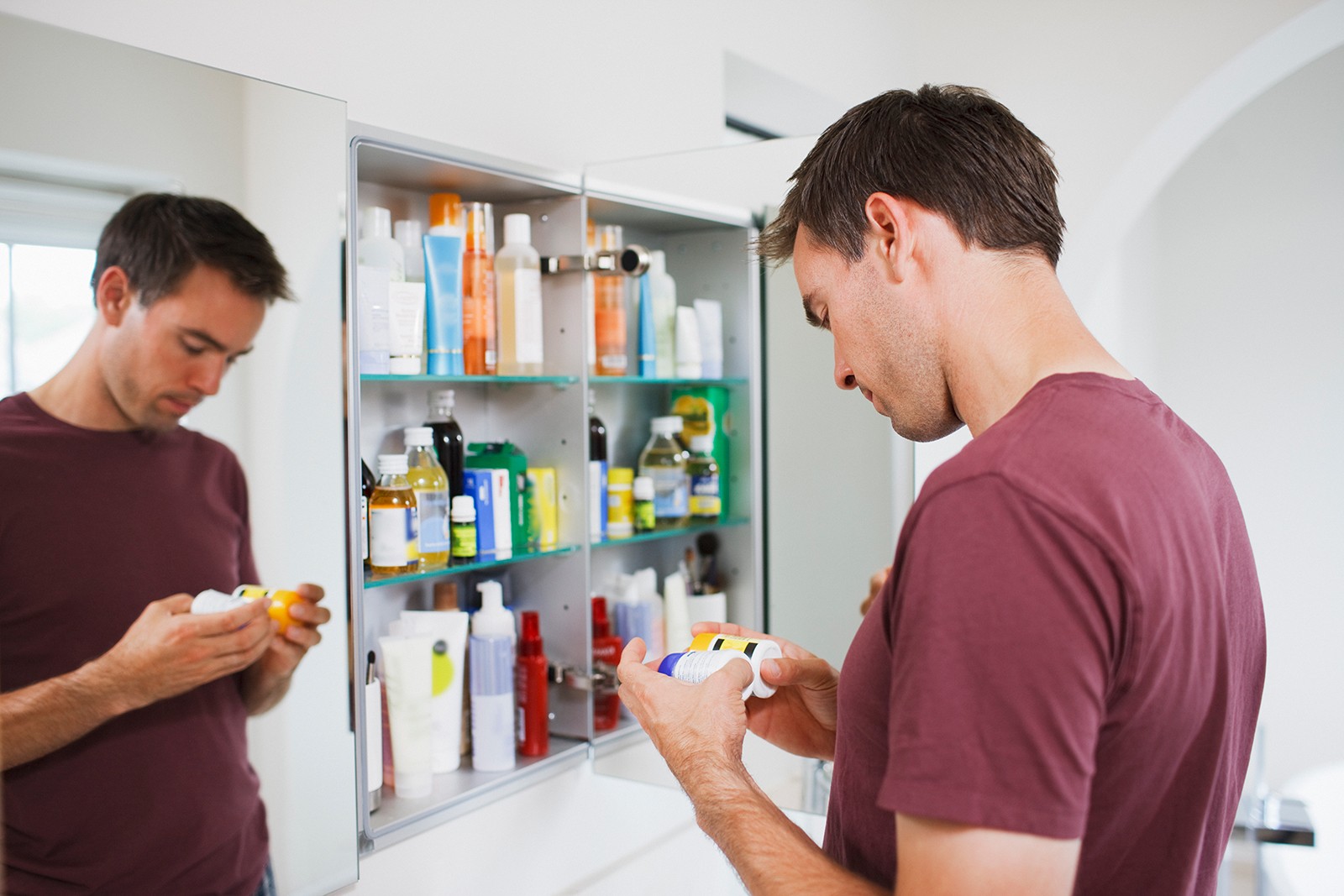 Overcoming addiction, man looking at pill bottles standing in front of the mirror.