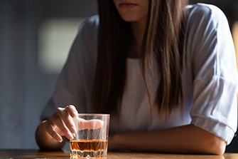Can Drinking Age Your Brain? New Study by USC Says Yes, woman sitting at a bar looking at an alcoholic drink.