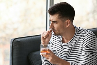 Coronavirus Quarantine and Binge Drinking, man in a stripped shirt holding a drink.