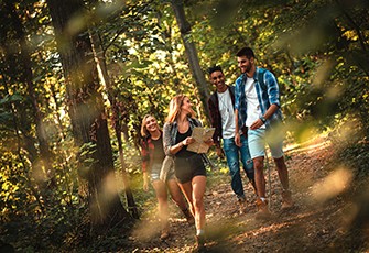 4 Tips on How to be There for a Loved One During Treatment, people walking in the woods on a trail laughing and talking.