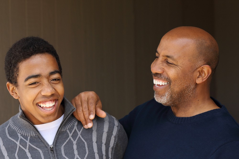 Two men laughing, a father and son helping with the addiction recovery healing process.