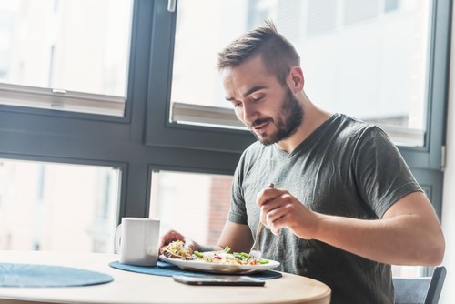 Happy man eating meal and having coffee in a restaurant