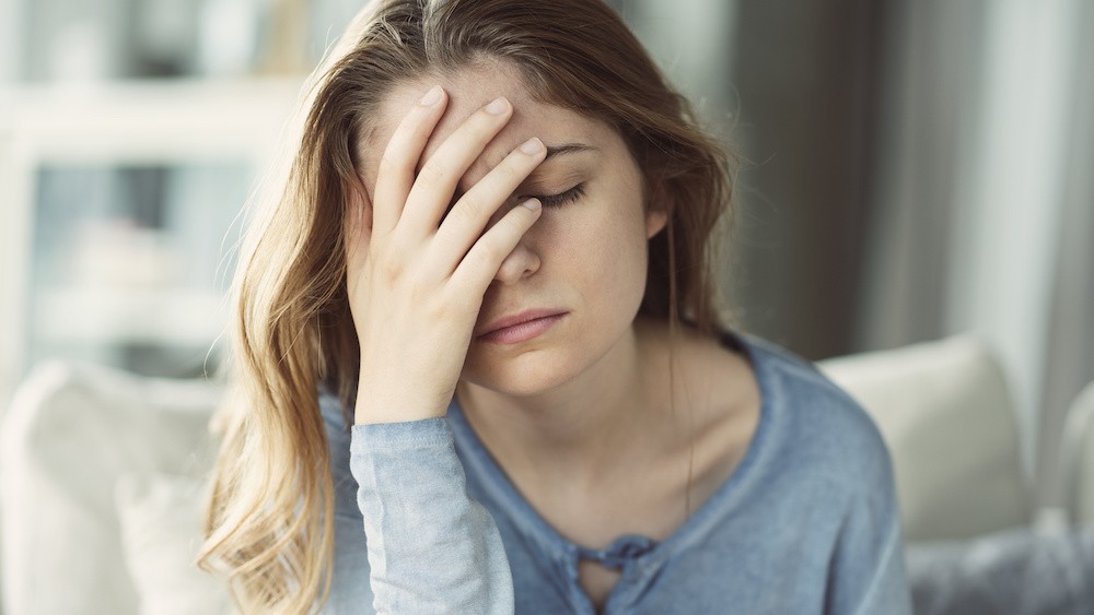 Woman with her hand on her face, thinking about drinking during the holidays.