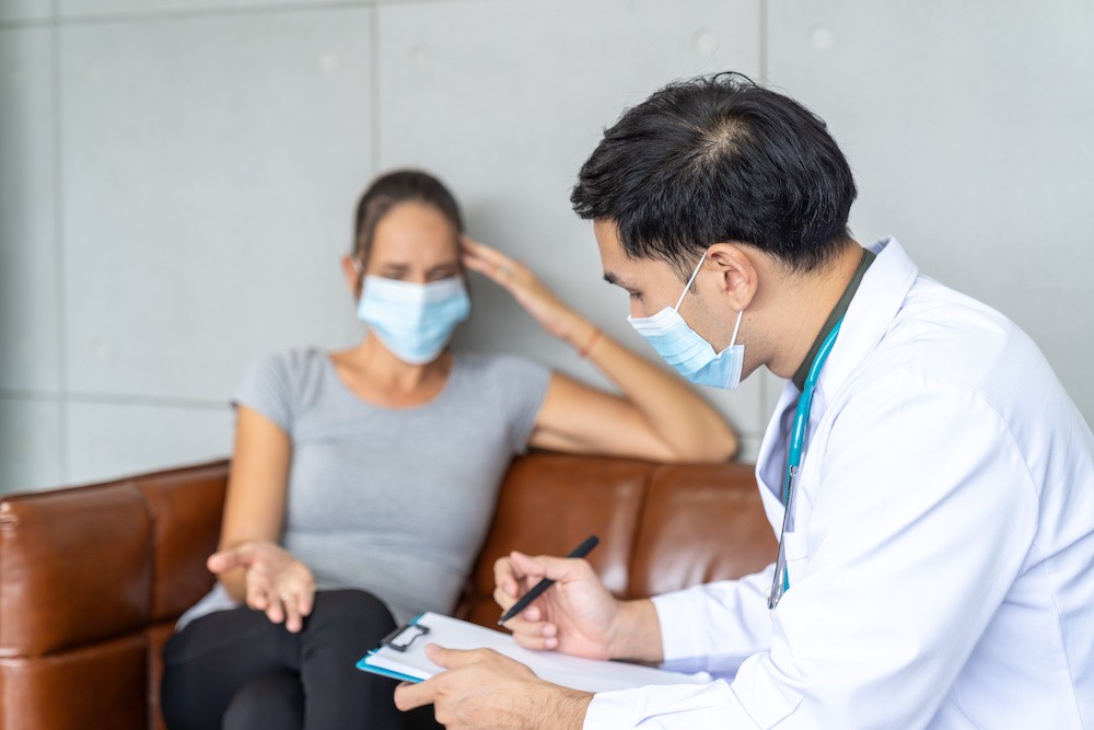 Woman with a mask on talking to a doctor on a couch, talking about opioids and dependence.