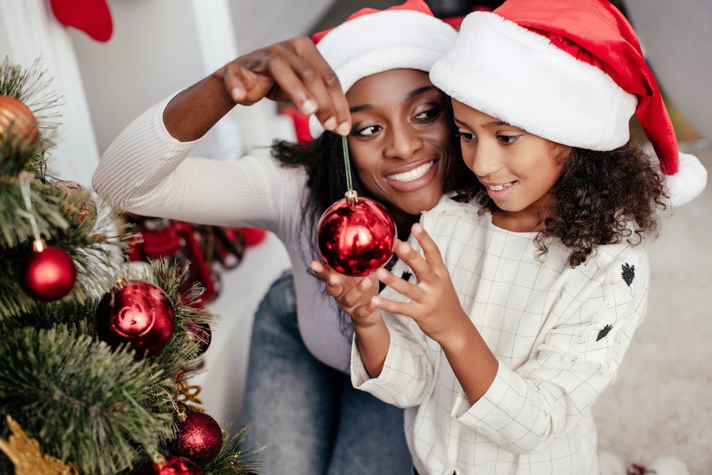 Two people decorating Christmas tree with red ornaments, talking about drugs and alcohol during the holidays.