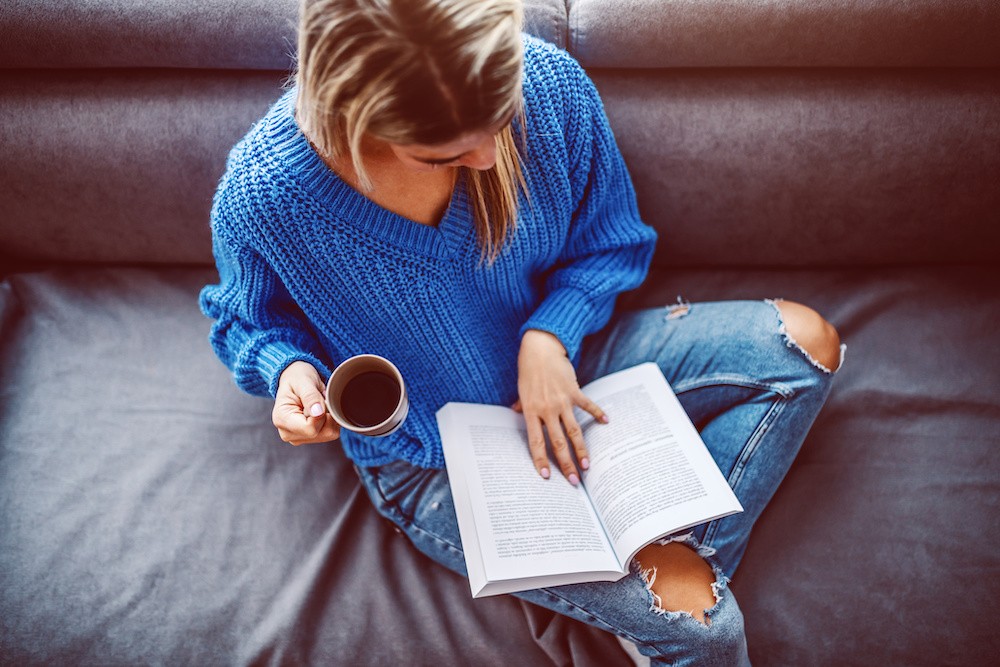 Woman in blue sweater reading at a sober living facility.