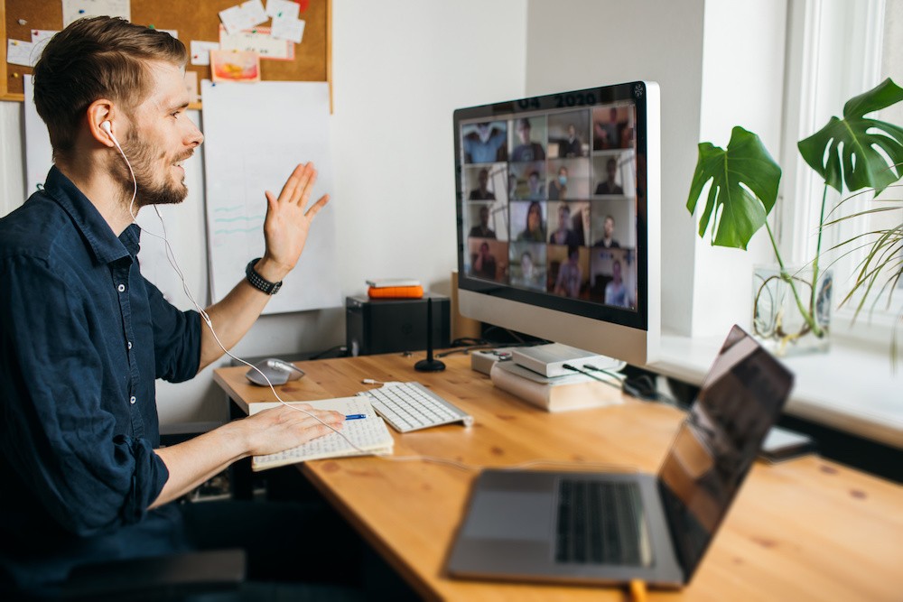 Man on Zoom Call - Therapy Depression, sitting at wooden desk with a desktop and laptop to right.