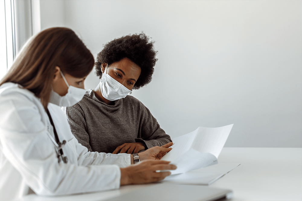 Person talking to her doctor about hepatitis, wearing masks.