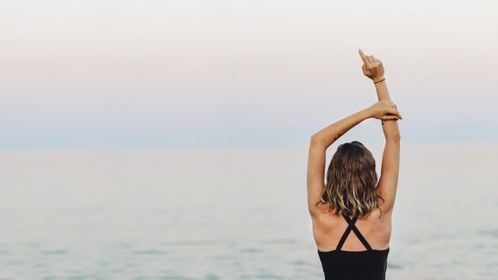 Woman stretching in front of the ocean, seeking privacy during addiction treatment.