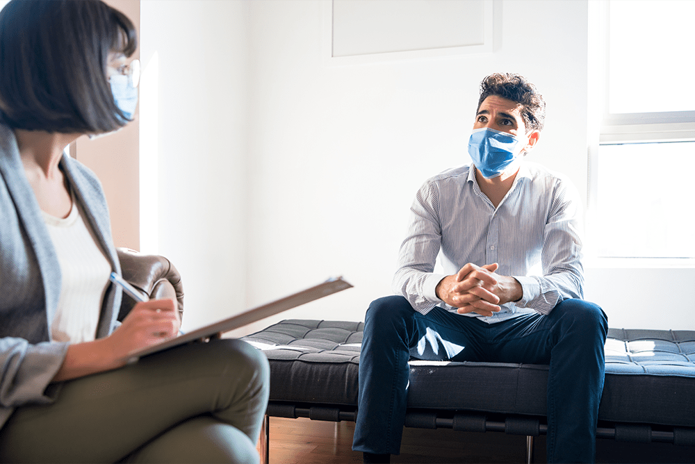 Two people with masks on talking about what addiction recovery looks like post pandemic.