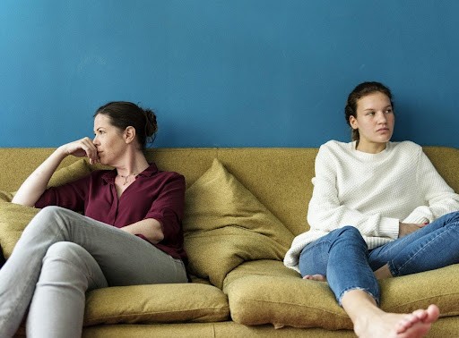 Tension between mom and daughter sitting on the couch, talking about what to do if your teen is still using even after treatment.