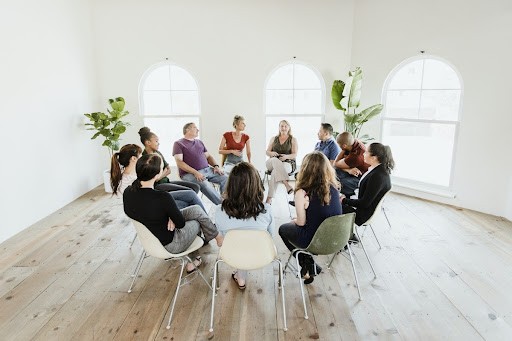 People in group therapy, talking in a circle about addiction recovery.