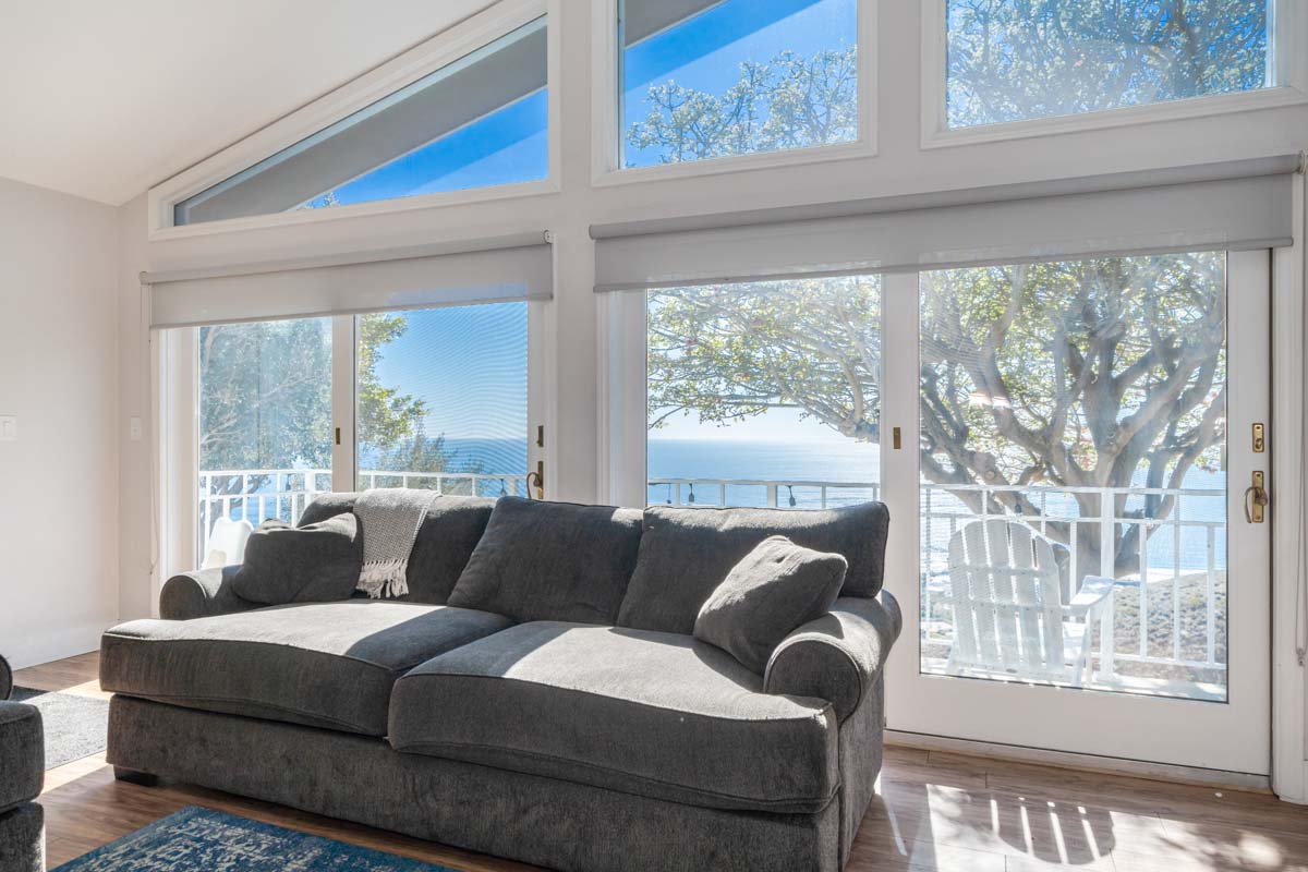View from the living room, large grey couch in front of doors out to the deck at Access Malibu, a residential treatment center in Malibu, California.