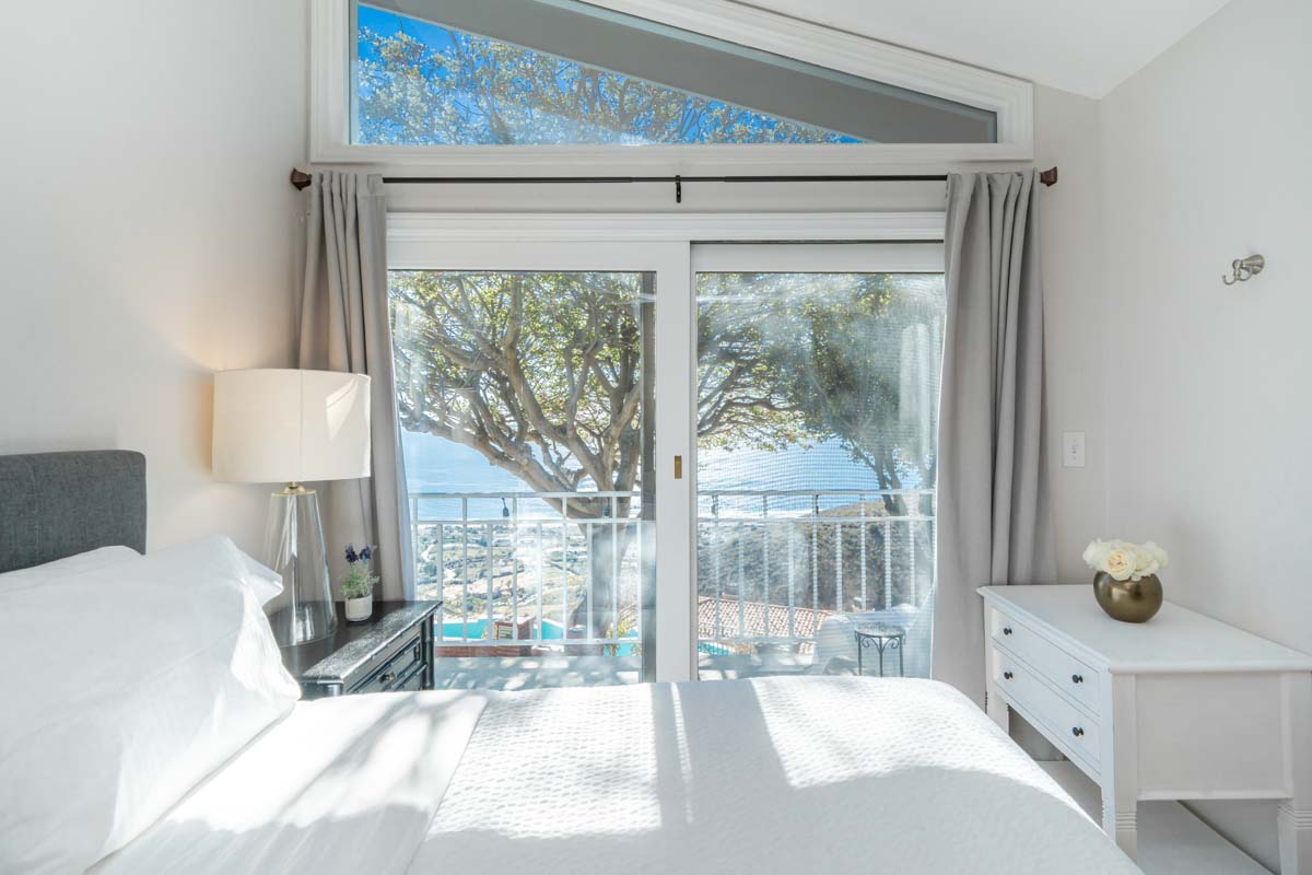 Large white single bed in front of large sliding doors at Access Malibu, a residential treatment center in Malibu, California.