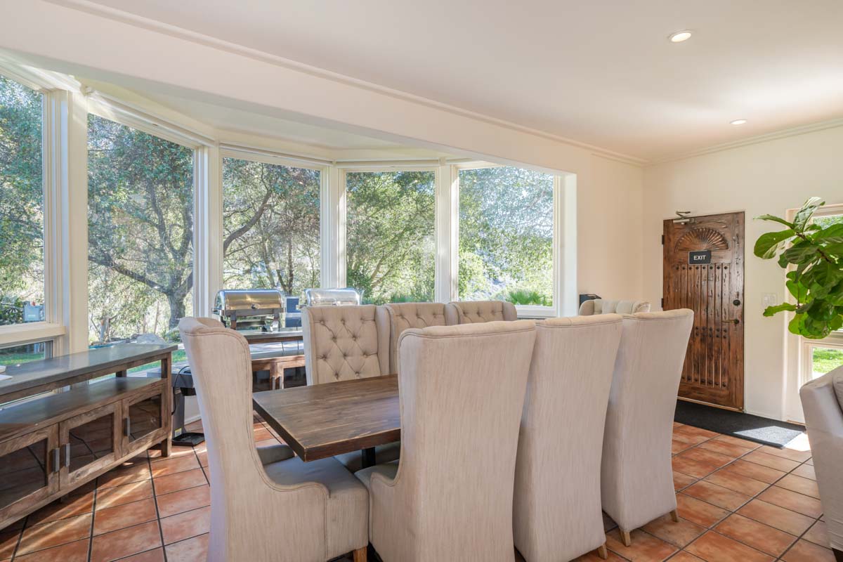 Dining room table in an open room with large floor to ceiling windows at Cliffside Malibu, a residential treatment center in Malibu, California.