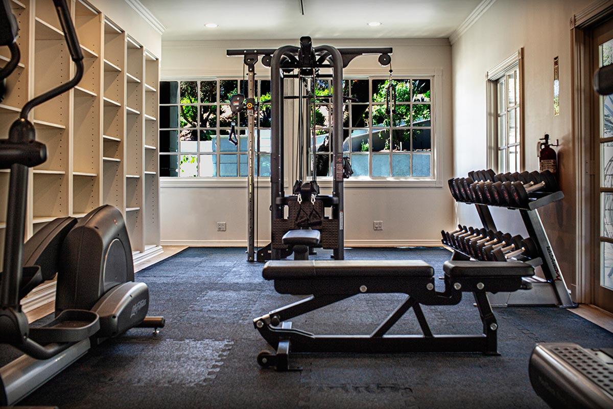 Picture of the gym at Sunset Malibu, a residential treatment center in Malibu, California. Large gym equipment in room with windows.