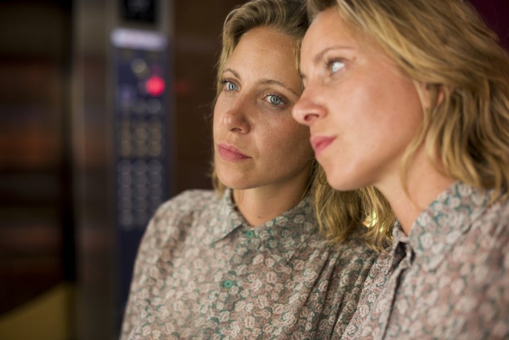 Woman looking into reflection against a mirror in an elevator thinking about co-occurring disorders in recovery.