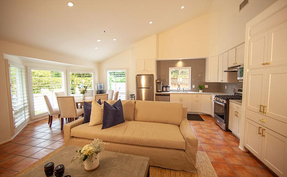 Pool house kitchen in Cliffside Malibu residential treatment house. Beige couch and table in front of a view of the kitchen in Malibu, California.