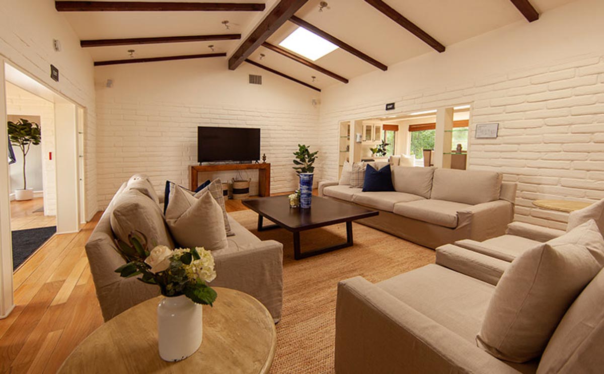 Living room with couches around a table at Cliffside Malibu, residential treatment house in Malibu, California.