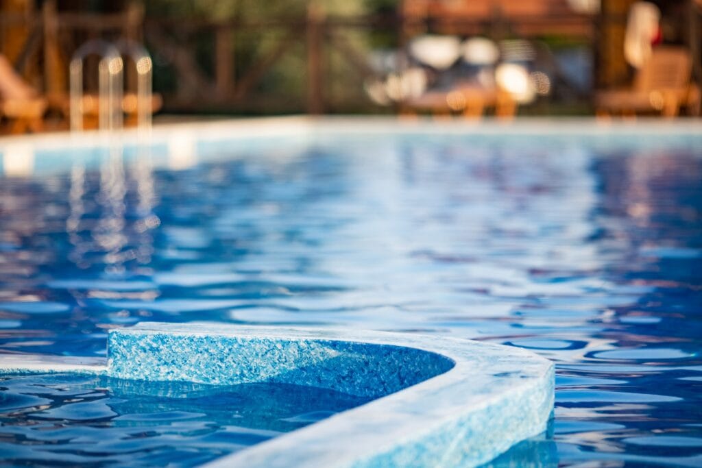 Top view of a large deep pool with clear transparent cool water with small light waves, on a summer vacation against the background of a warm bright sunset